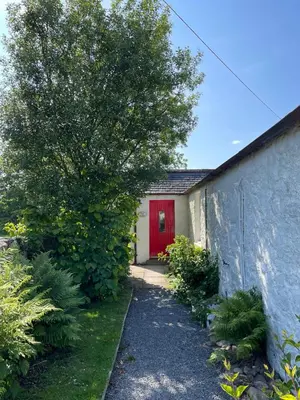 a house with a red door and a tree at Barcloy Milk House in Kirkcudbright