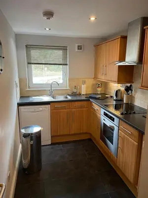 a kitchen with wooden cabinets and a sink and a window at Portpatrick 2 bedroom Self Catering Flat in Portpatrick