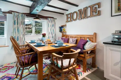 a dining room with a wooden table and chairs at Bridge End Cottage Elterwater in Ambleside