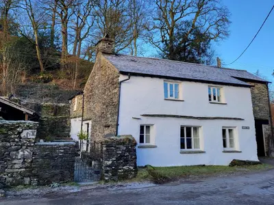 an old white house with a chimney on a street at Bridge End Cottage Elterwater in Ambleside