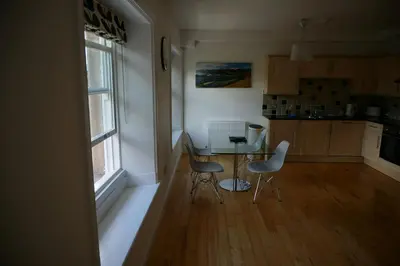 a kitchen with a table and chairs next to a window at Chaucer View, Chaucer House Apts in Keswick