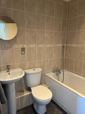 a bathroom with a toilet and a sink and a tub at Chaucer View, Chaucer House Apts in Keswick