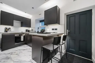 a kitchen with black cabinets and a bar with stools at Modern Town House In Cockermouth in Cockermouth