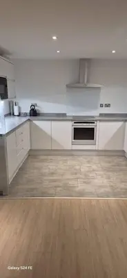 a kitchen with white appliances and a wooden floor at Apartment In Canary Wharf, London in Moffat