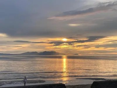 a person standing on the beach at sunset at Church Cottage with sunny garden in Ayr