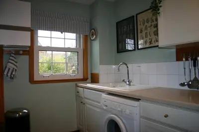 a kitchen with a sink and a washing machine at Church Cottage with sunny garden in Ayr