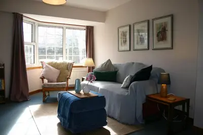 a living room with a blue couch and a chair at Church Cottage with sunny garden in Ayr