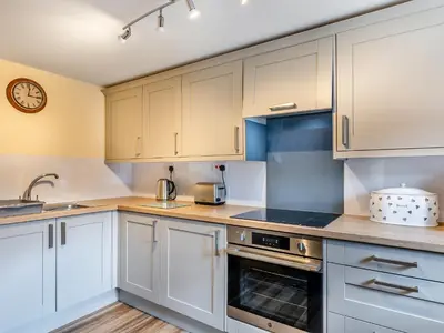 a kitchen with white cabinets and a clock on the wall at Turnip House - Uk48909 in Allonby