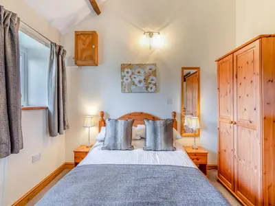 a bedroom with a bed with blue pillows at Eight Byre - Uk48913 in Allonby