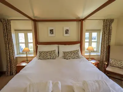 a bedroom with a large white bed with two windows at Squirrel Cottage in Keswick