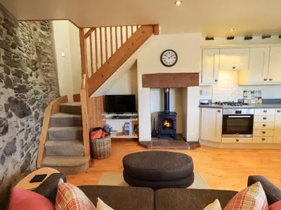 a living room with a staircase and a kitchen at Squirrel Cottage in Keswick