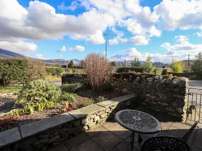 a patio with a stone wall and a table at Squirrel Cottage in Keswick