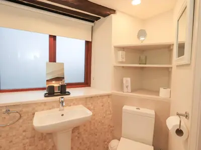 a bathroom with a sink and a toilet and a window at Jasmine Cottage in Keswick