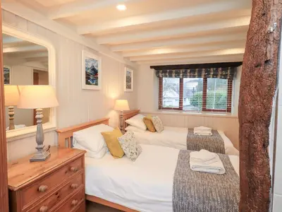 a bedroom with two beds and a mirror at Jasmine Cottage in Keswick