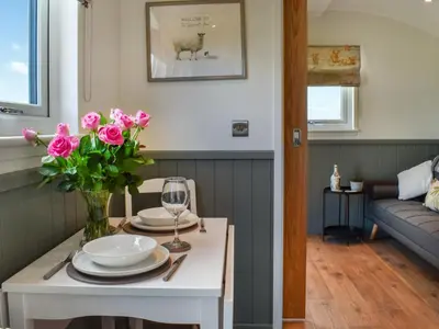 a living room with a table with pink flowers on it at Meadows View Shepherd's Hut in Cockermouth