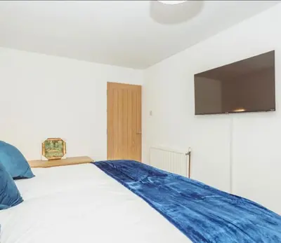 a bedroom with a bed with a tv on the wall at Caul View Apartment in Dumfries