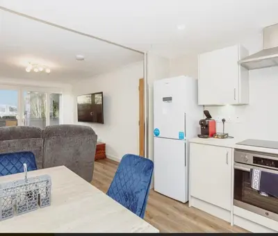 a kitchen and a living room with a white refrigerator at Caul View Apartment in Dumfries