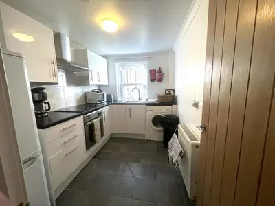 a kitchen with white cabinets and a washer and dryer at Campbell Cottage in Biggar