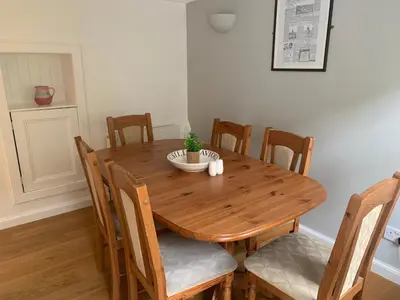 a wooden dining room table with chairs and a plant on it at Campbell Cottage in Biggar