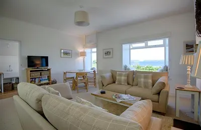 a living room with two couches and a table at Meadow Cottage in Girthon