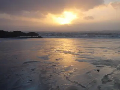 a sunset on the beach with the tide coming in at Muir Lodge in Gatehouse of Fleet