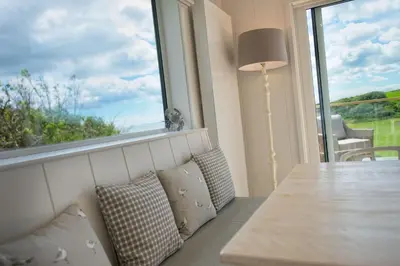 a living room with a table and a large window at Muir Lodge in Gatehouse of Fleet