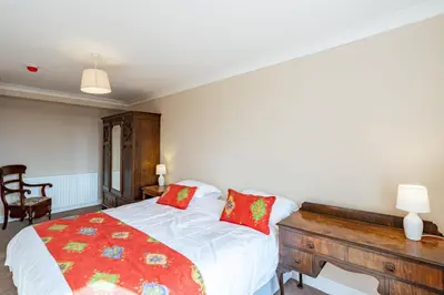 a bedroom with a bed with red pillows on it at Ornockenoch House in Gatehouse of Fleet