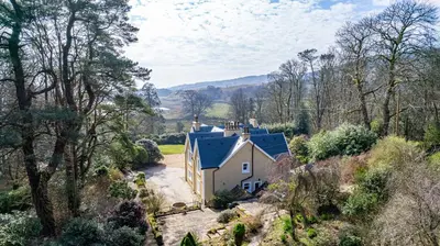 an aerial view of a house on a hill with trees at Ornockenoch House in Gatehouse of Fleet