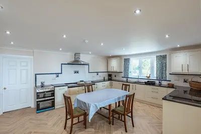 a kitchen with a table and some chairs in it at Ornockenoch House in Gatehouse of Fleet