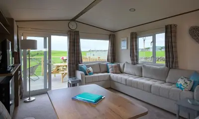 a living room with a couch and a table at Pebbles in Girthon