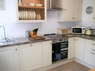 a kitchen with white cabinets and a stove top oven at Primrose Cottage in Rockcliffe