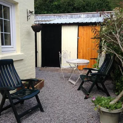a patio with two chairs and a table and a fence at Primrose Cottage in Rockcliffe