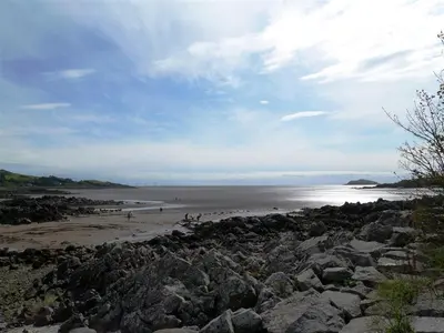 a beach with rocks and people on the beach at Primrose Cottage in Rockcliffe