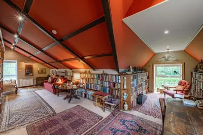 a living room with orange walls and bookshelves at The Mill in Castle Douglas