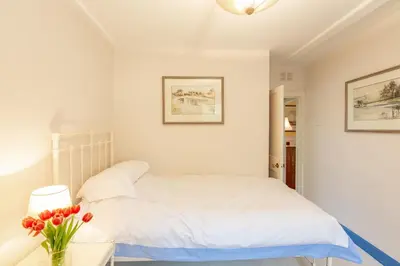 a white bedroom with a bed and a vase of flowers at The Miller's House in Castle Douglas