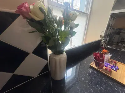 a white vase with flowers in it on a counter at The Hidden Hicks - Sleeps 2 in Whitehaven