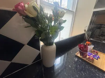 a white vase with flowers in it on a counter at The Hidden Hicks - Sleeps 2 in Whitehaven