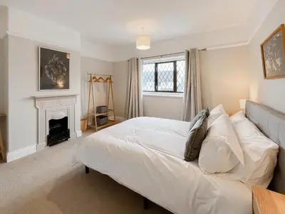 a bedroom with a white bed and a fireplace at Hindsgarth in Keswick