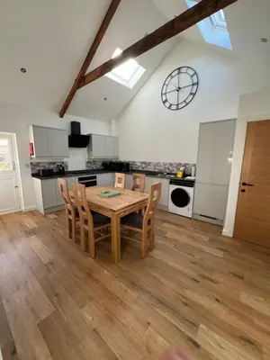 a kitchen and dining room with a wooden table and chairs at Oystercatcher in Dalby