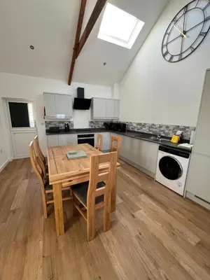a kitchen with a wooden table and chairs and a clock at Oystercatcher in Dalby