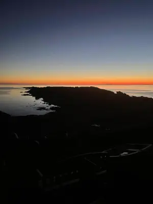 a sunset over a body of water with a mountain at Oystercatcher in Dalby