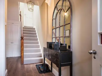 a hallway with a dresser and a mirror and stairs at Skyfell House in Keswick