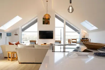 a living room with white furniture and large windows at 2 Kippford Slipway in Kippford