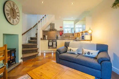 a living room with a blue couch and a kitchen at Bell Cottage - Cockermouth is five minutes walk to pubs, restaurants and shops in Cockermouth