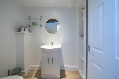 a white bathroom with a sink and a mirror at Bell Cottage - Cockermouth is five minutes walk to pubs, restaurants and shops in Cockermouth