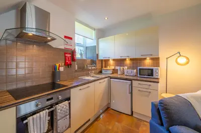 a kitchen with white cabinets and a stove top oven at Bell Cottage - Cockermouth is five minutes walk to pubs, restaurants and shops in Cockermouth