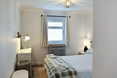 a small bedroom with a bed and a window at Barassie Bay View apartment in Troon