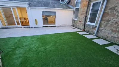a patio with a green lawn in front of a house at 5 Bedrooms Sleeps 10 Full Kitchen Parking in Ayr