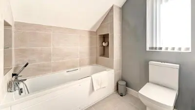 a white bathroom with a tub and a toilet at Skiddaw Heights in Keswick