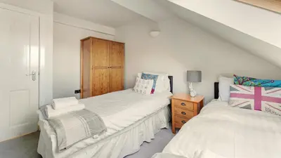 a bedroom with two beds and a wooden cabinet at Skiddaw Heights in Keswick